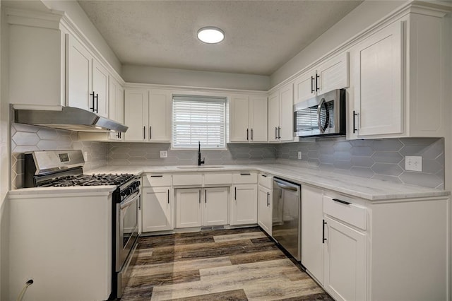 220 E 31st St, Edmond, OK 73013 - kitchen with stainless steel appliances, under cabinet range hood, a textured ceiling, and white cabinetry