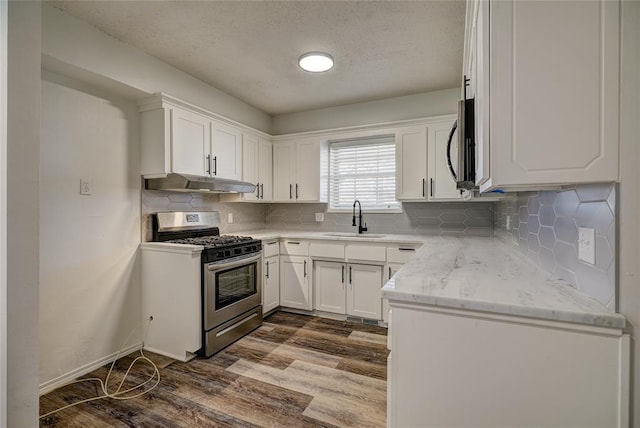220 E 31st St, Edmond, OK 73013 - kitchen with stainless steel appliances, under cabinet range hood, dark wood-style flooring, white cabinetry, and a textured ceiling