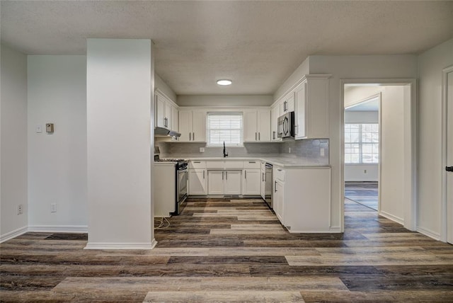 220 E 31st St, Edmond, OK 73013 - kitchen featuring appliances with stainless steel finishes, a textured ceiling, dark wood finished floors, under cabinet range hood, and white cabinets