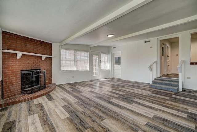 220 E 31st St, Edmond, OK 73013 - unfurnished living room with wood finished floors, stairway, a brick fireplace, and beamed ceiling