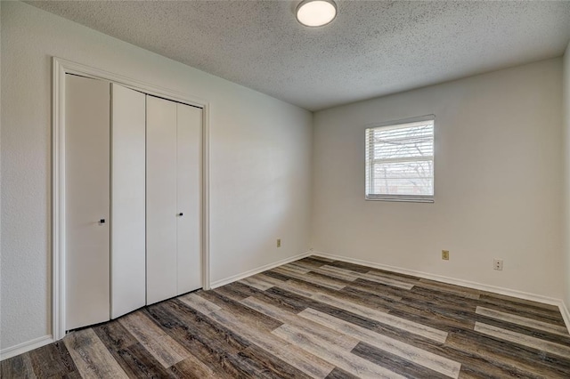 220 E 31st St, Edmond, OK 73013 - unfurnished bedroom with dark wood finished floors, a textured ceiling, and a closet