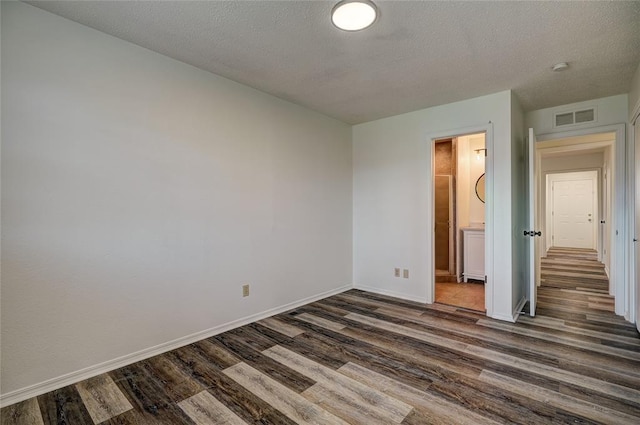 220 E 31st St, Edmond, OK 73013 - unfurnished bedroom with dark wood-style flooring, a textured ceiling, and ensuite bathroom