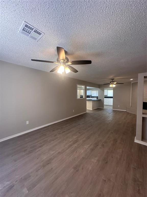 6708 Lyrewood Cir, Oklahoma City, OK 73132 - unfurnished living room featuring a ceiling fan, a textured ceiling, and dark wood finished floors