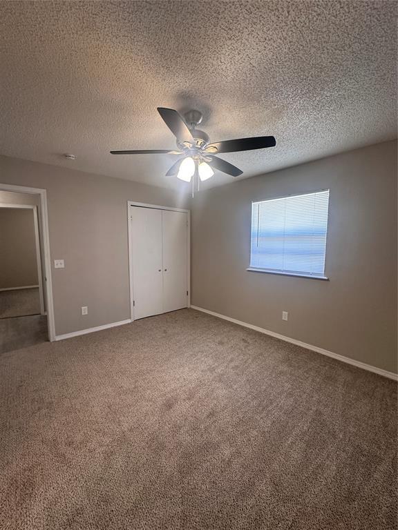 6708 Lyrewood Cir, Oklahoma City, OK 73132 - unfurnished bedroom with carpet flooring, a closet, a textured ceiling, and ceiling fan