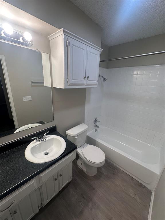 6708 Lyrewood Cir, Oklahoma City, OK 73132 - bathroom featuring wood finished floors, shower / washtub combination, vanity, and a textured ceiling