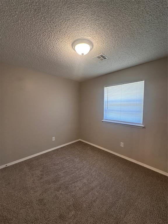 6708 Lyrewood Cir, Oklahoma City, OK 73132 - empty room with dark colored carpet and a textured ceiling