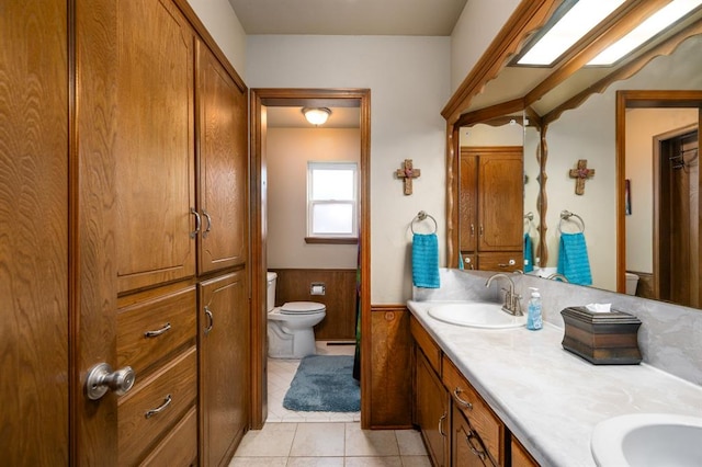 2504 NW 119th St, Oklahoma City, OK 73120 - bathroom with double vanity, wainscoting, tile patterned flooring, a closet, and baseboard heating