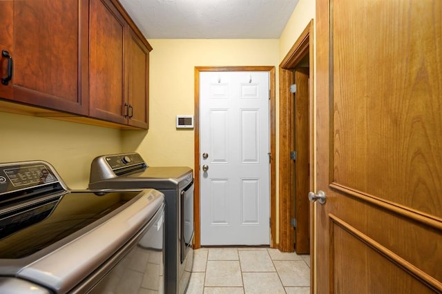 2504 NW 119th St, Oklahoma City, OK 73120 - washroom featuring washing machine and clothes dryer, cabinet space, light tile patterned flooring, and a textured ceiling
