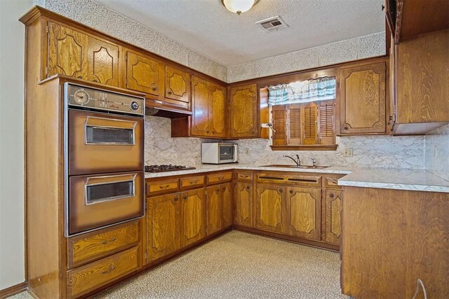 3913 SE 14th Pl, Oklahoma City, OK 73115 - kitchen with double oven, brown cabinets, a textured ceiling, and decorative backsplash