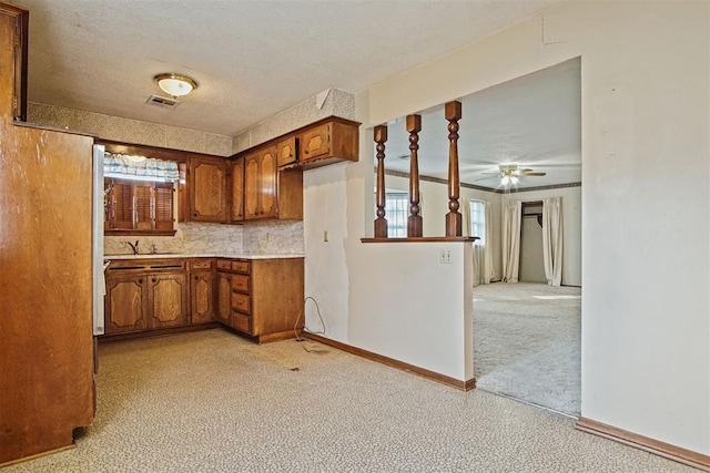 3913 SE 14th Pl, Oklahoma City, OK 73115 - kitchen featuring brown cabinetry, a ceiling fan, light countertops, a textured ceiling, and backsplash