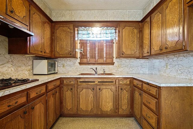 3913 SE 14th Pl, Oklahoma City, OK 73115 - kitchen featuring appliances with stainless steel finishes, range hood, brown cabinets, and a textured ceiling