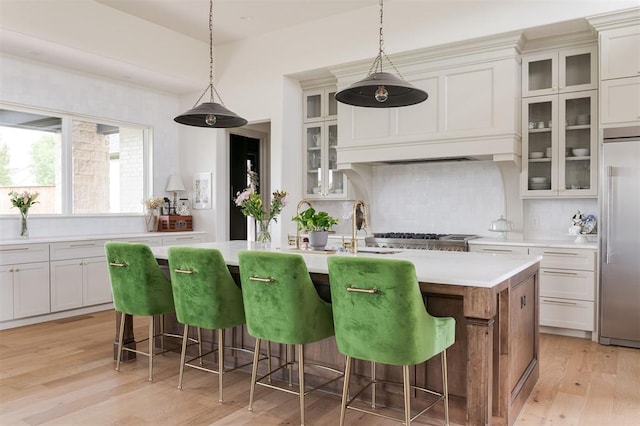 501 Old Creek Rd, Edmond, OK 73034 - kitchen featuring built in refrigerator, light countertops, decorative backsplash, an island with sink, and light wood-style floors