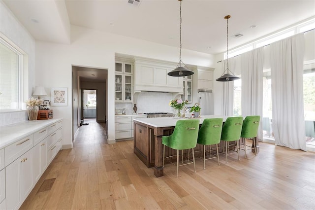 501 Old Creek Rd, Edmond, OK 73034 - kitchen with premium range hood, an island with sink, light wood-style floors, and a kitchen bar