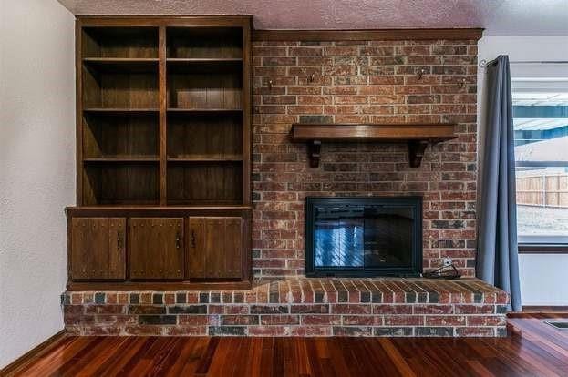 2912 Smiling Hill Blvd, Edmond, OK 73013 - unfurnished living room with wood finished floors and a brick fireplace