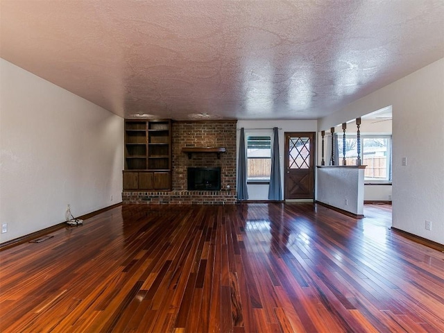 2912 Smiling Hill Blvd, Edmond, OK 73013 - unfurnished living room with wood-type flooring, a textured ceiling, plenty of natural light, and a fireplace