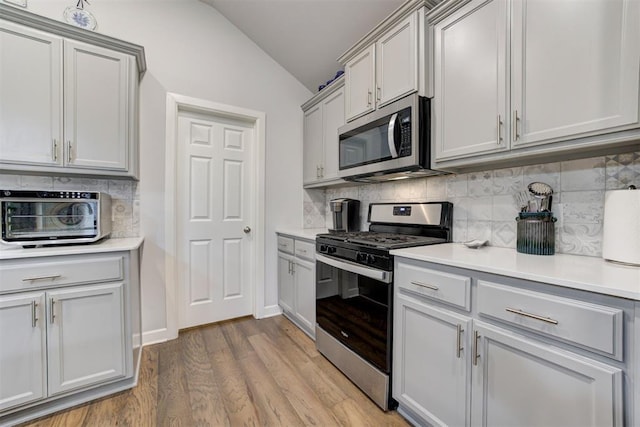 2161 Native Dancer Dr, Choctaw, OK 73020 - kitchen with appliances with stainless steel finishes, lofted ceiling, backsplash, light countertops, and light wood finished floors