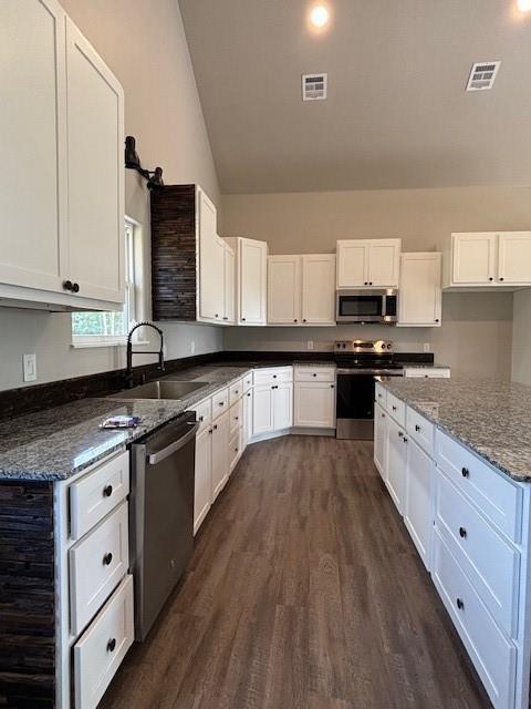 379100 E 1100th Rd, Okemah, OK 74859 - kitchen with stainless steel appliances, dark wood-style floors, white cabinets, dark stone counters, and high vaulted ceiling