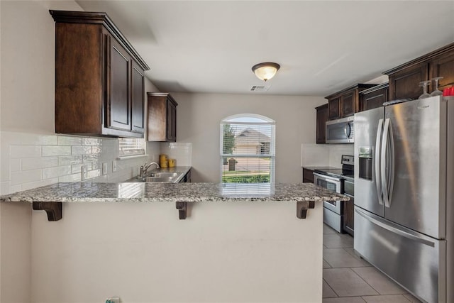 4116 NW 154th St, Edmond, OK 73013 - kitchen featuring appliances with stainless steel finishes, dark brown cabinets, decorative backsplash, and a peninsula