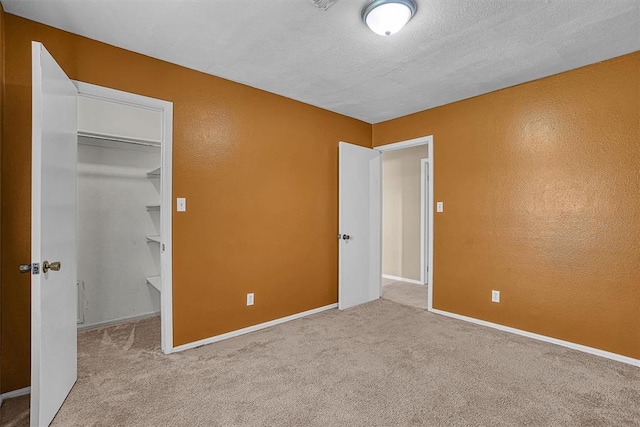 908 S Trail Dr, Altus, OK 73521 - unfurnished bedroom featuring a spacious closet, carpet flooring, a textured wall, and a closet