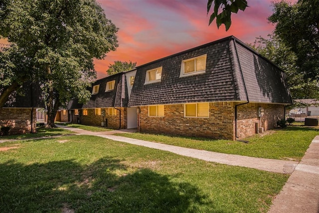 6220 S Douglas Ave, Oklahoma City, OK 73139 - back of house at dusk with mansard roof, a yard, brick siding, and roof with shingles