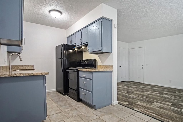 6220 S Douglas Ave, Oklahoma City, OK 73139 - kitchen featuring black appliances, a textured ceiling, light tile patterned floors, ventilation hood, and gray cabinets