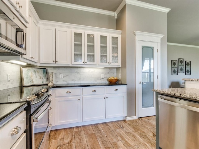 7313 Jack Dr, Oklahoma City, OK 73132 - kitchen with appliances with stainless steel finishes, crown molding, white cabinetry, tasteful backsplash, and light wood finished floors