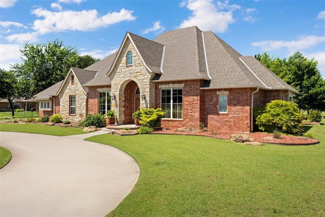 227 Quail Hollow Way, Choctaw, OK 73020 - french country home with a front lawn, a shingled roof, and stone siding