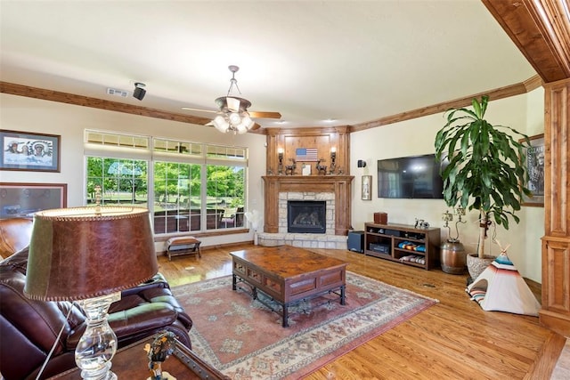 227 Quail Hollow Way, Choctaw, OK 73020 - living area featuring a ceiling fan, wood finished floors, a stone fireplace, and crown molding