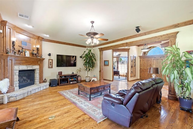 227 Quail Hollow Way, Choctaw, OK 73020 - living room featuring ceiling fan, wood finished floors, ornamental molding, and a stone fireplace