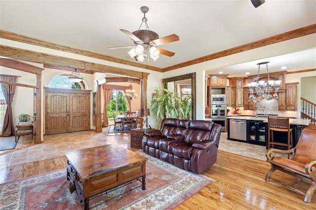 227 Quail Hollow Way, Choctaw, OK 73020 - living room featuring a chandelier, a ceiling fan, ornamental molding, and light wood-style flooring