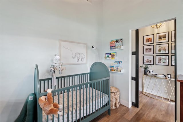 80 E Shore Dr, Arcadia, OK 73007 - bedroom with wood finished floors, a crib, and a chandelier