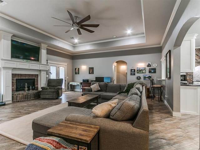 2395 County Road 1260, Blanchard, OK 73010 - living area featuring arched walkways, ceiling fan, a brick fireplace, crown molding, and a raised ceiling