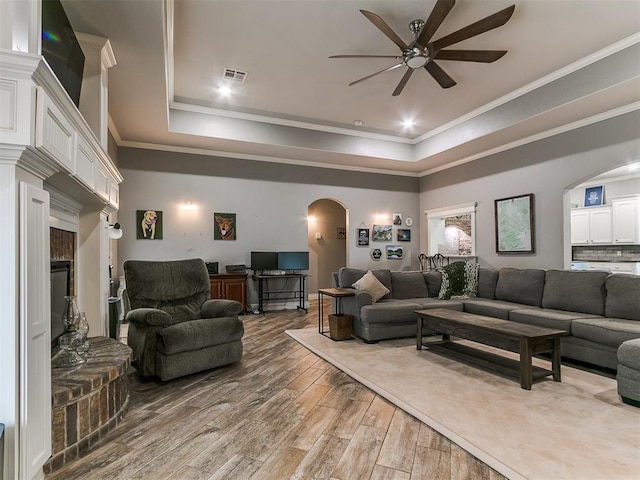 2395 County Road 1260, Blanchard, OK 73010 - living room featuring arched walkways, a ceiling fan, a raised ceiling, wood finished floors, and ornamental molding