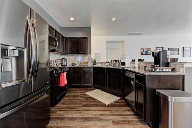 11704 NW 135th Ter, Piedmont, OK 73078 - kitchen with stainless steel appliances, a peninsula, dark wood-style floors, light stone countertops, and tasteful backsplash