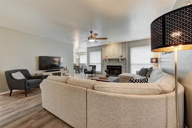 8517 SW 36th Ter, Oklahoma City, OK 73179 - living room with a ceiling fan, wood finished floors, a fireplace, and a textured ceiling