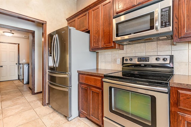 2524 Faint Ridge Way, Piedmont, OK 73078 - kitchen with appliances with stainless steel finishes, light tile patterned floors, dark countertops, and backsplash