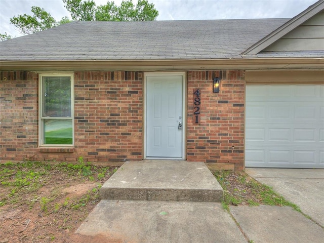 4821 Cinderella Dr, Oklahoma City, OK 73129 - view of exterior entry with brick siding, roof with shingles, and an attached garage