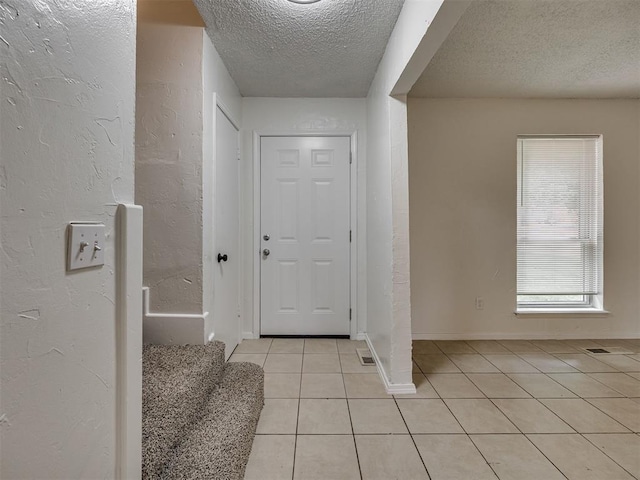 4821 Cinderella Dr, Oklahoma City, OK 73129 - entrance foyer featuring a textured ceiling, light tile patterned floors, a textured wall, and stairs