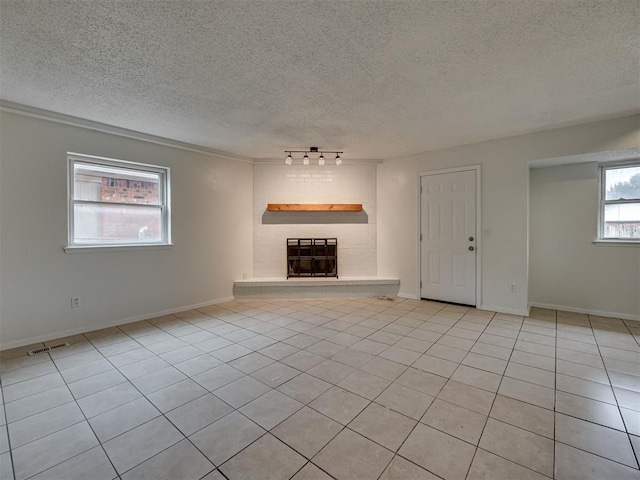 4821 Cinderella Dr, Oklahoma City, OK 73129 - unfurnished living room featuring a textured ceiling, light tile patterned floors, a brick fireplace, and rail lighting