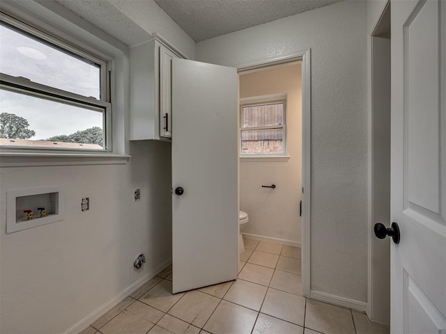 4821 Cinderella Dr, Oklahoma City, OK 73129 - laundry area featuring cabinet space, hookup for an electric dryer, hookup for a washing machine, a textured ceiling, and light tile patterned floors