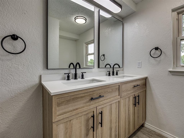 4821 Cinderella Dr, Oklahoma City, OK 73129 - bathroom with a textured wall, double vanity, wood finished floors, and a textured ceiling