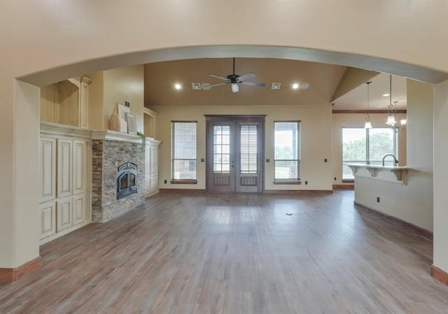 30202 Sleepy Hollow Dr, Mcloud, OK 74851 - unfurnished living room with vaulted ceiling, wood finished floors, arched walkways, a stone fireplace, and ceiling fan