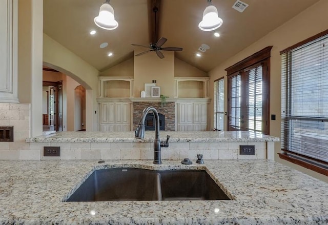 30202 Sleepy Hollow Dr, Mcloud, OK 74851 - kitchen featuring a fireplace, arched walkways, a ceiling fan, and light stone counters
