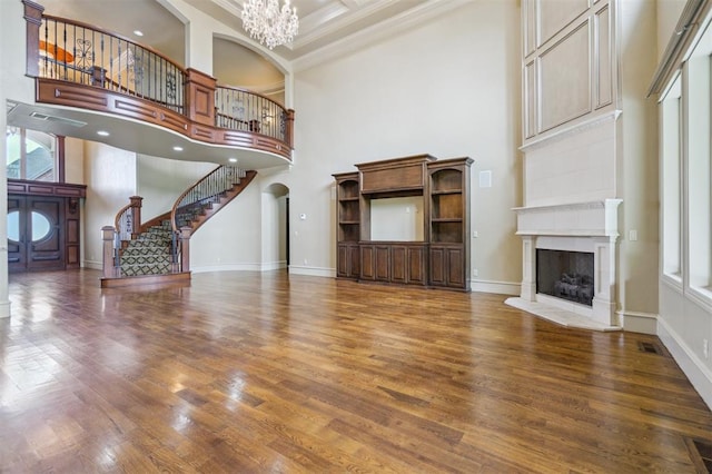 13209 Blue Canyon Cir, Oklahoma City, OK 73142 - unfurnished living room with a towering ceiling, a chandelier, wood finished floors, a fireplace, and crown molding