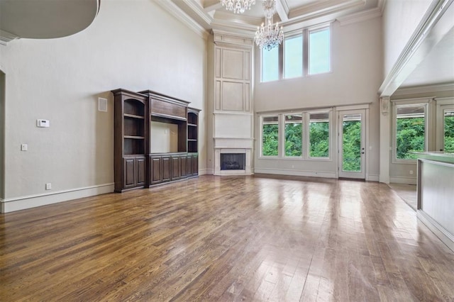 13209 Blue Canyon Cir, Oklahoma City, OK 73142 - unfurnished living room featuring a high ceiling, a chandelier, wood finished floors, crown molding, and a fireplace
