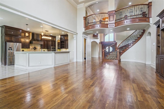 13209 Blue Canyon Cir, Oklahoma City, OK 73142 - unfurnished living room with arched walkways, a high ceiling, decorative columns, stairs, and wood finished floors