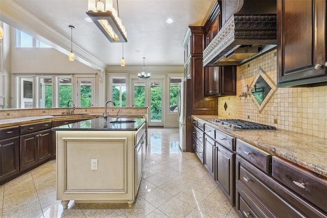 13209 Blue Canyon Cir, Oklahoma City, OK 73142 - kitchen featuring appliances with stainless steel finishes, custom exhaust hood, a chandelier, crown molding, and an island with sink