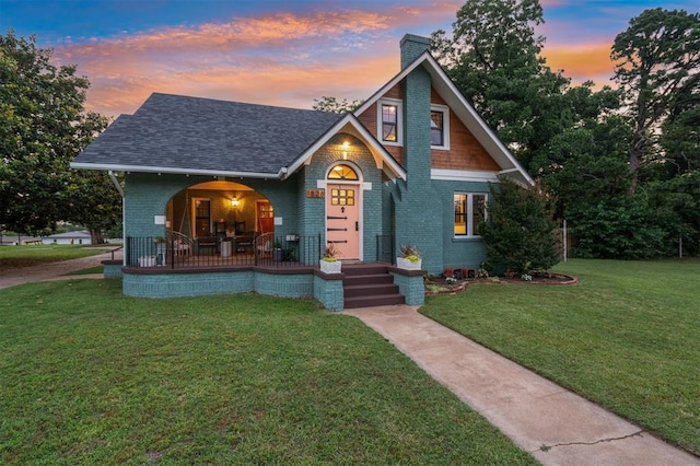 1828 S 7th St, Chickasha, OK 73018 - view of front of house featuring a chimney, a porch, a front yard, brick siding, and roof with shingles