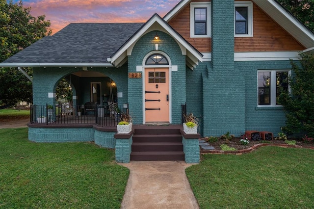 1828 S 7th St, Chickasha, OK 73018 - view of front facade with brick siding, covered porch, and a front yard