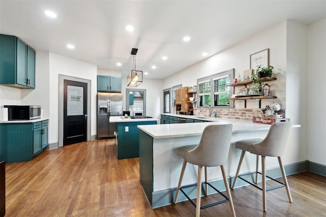 1828 S 7th St, Chickasha, OK 73018 - kitchen featuring appliances with stainless steel finishes, a peninsula, a kitchen island, light wood finished floors, and recessed lighting